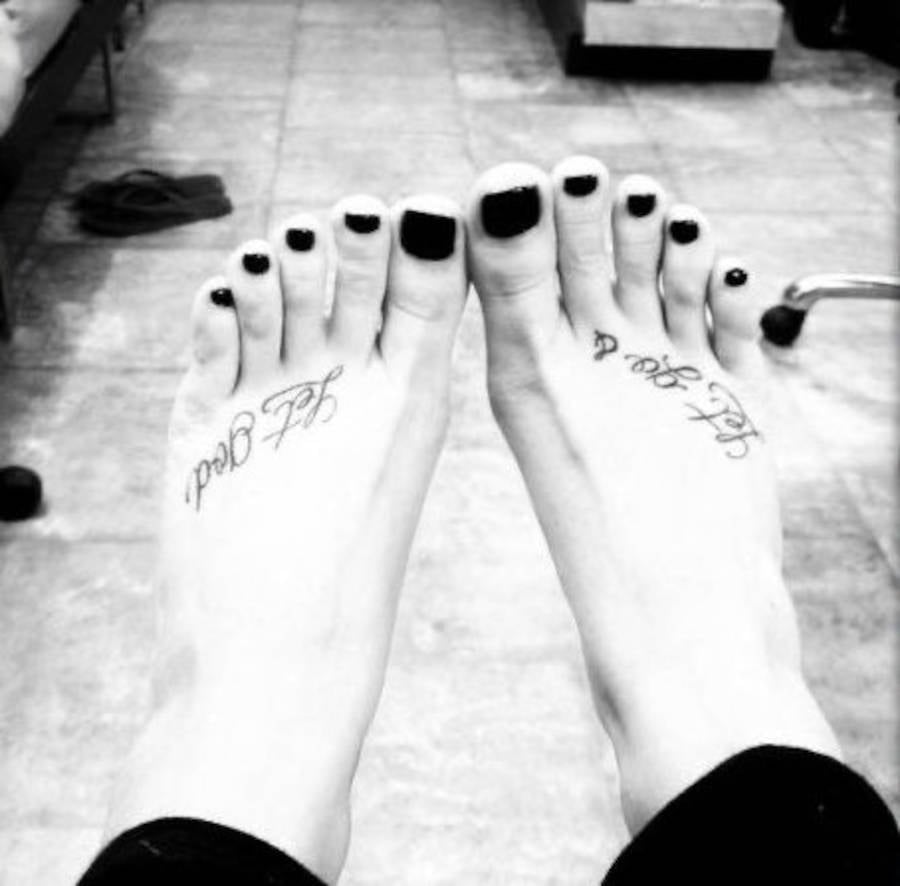 Foto em preto e branca dos pés de Demi Lovato com a tatuagem "Let Go & Let God"