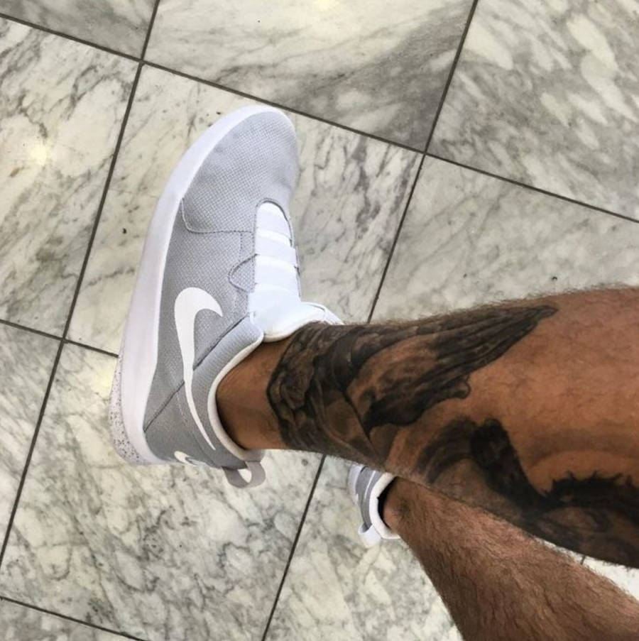 Foto de perna do Justin Bieber com a sua tatuagem de mãos em oração e tênis da nike