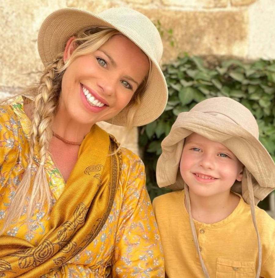 Foto de Karina Bacchi com o seu filho Enrico Bacchi, ambos de roupas amarelas e chápeu