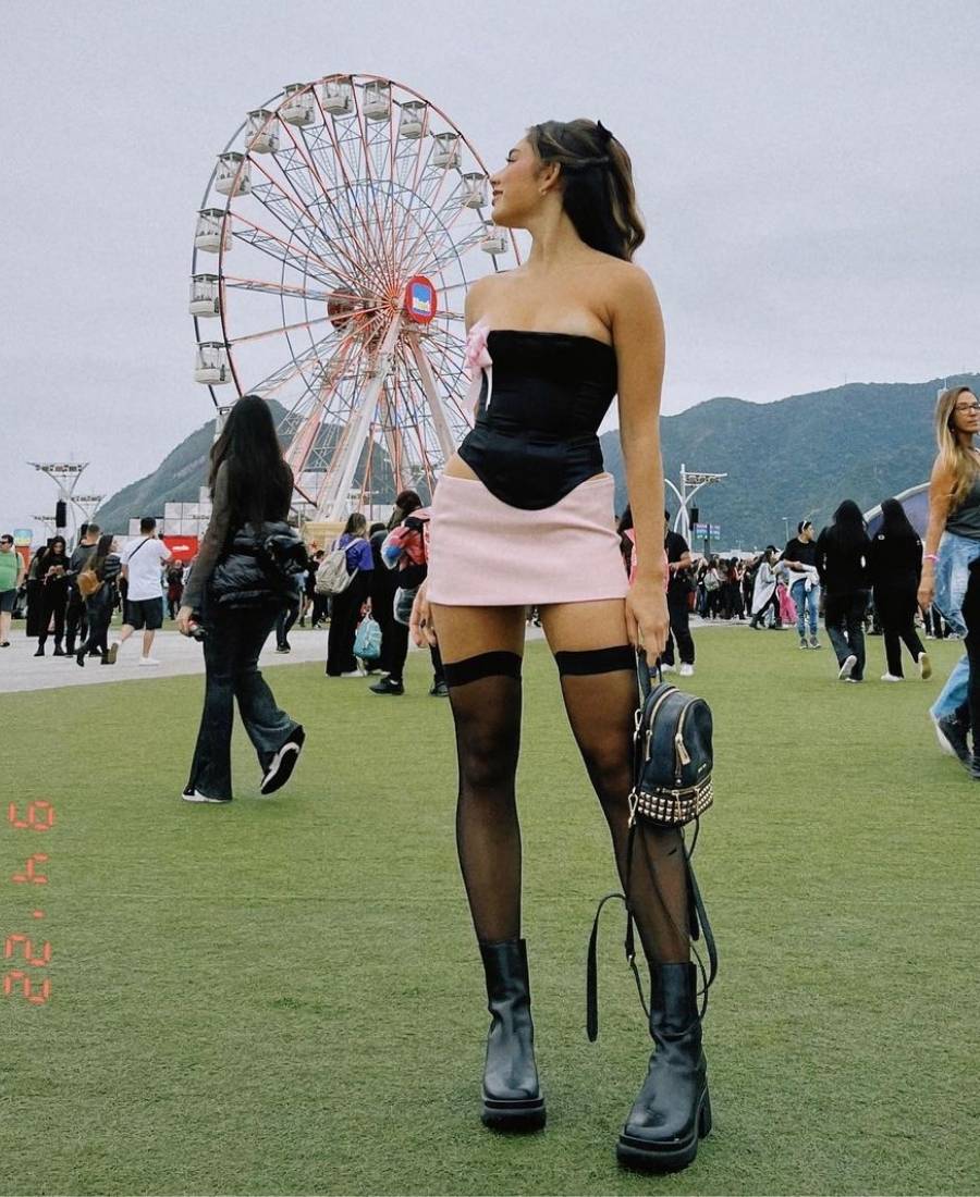 Julia Rocha Cardoso usando corset preto com saia rosa, meias finas e botas