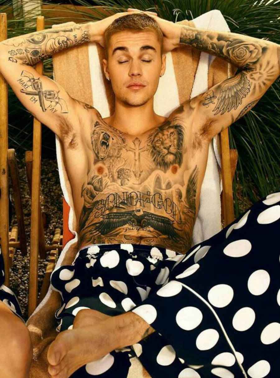 Foto de Justin Bieber com os olhos fechados e as mãos na cabeça, vestido uma calça de pijama de bolinhas