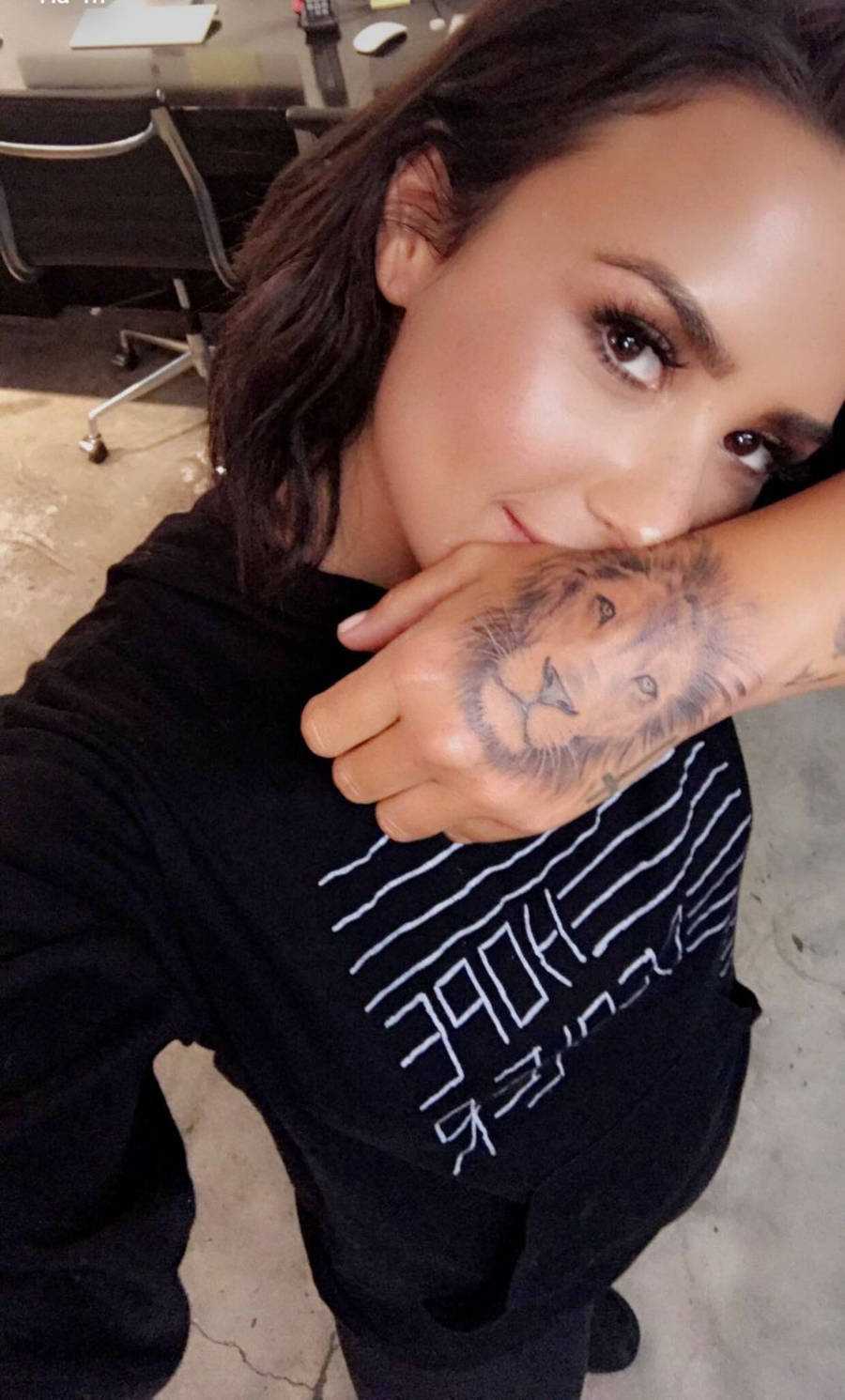Foto de Demi mostrando sua tatuagem de leão na mão