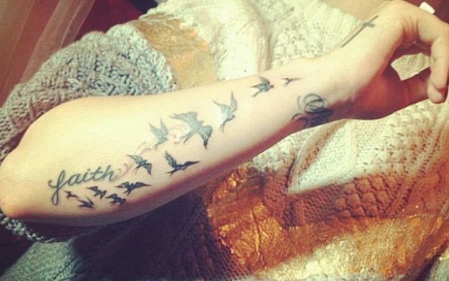 Foto da tatuagem de Demi, com a palavra faith e os pássaros voando