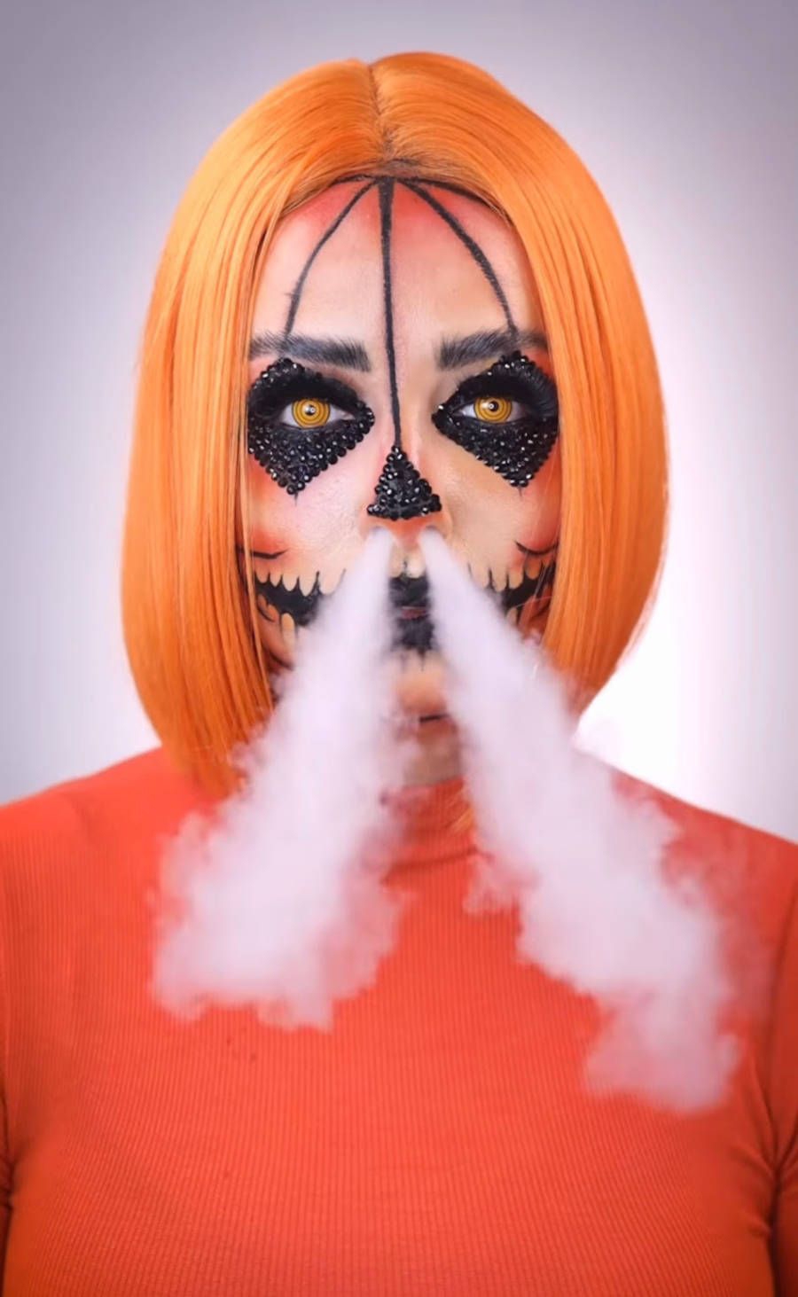 Foto de Jessica Cardoso com maquiagem de abóbora para o Halloween soltando fumaça pelo nariz