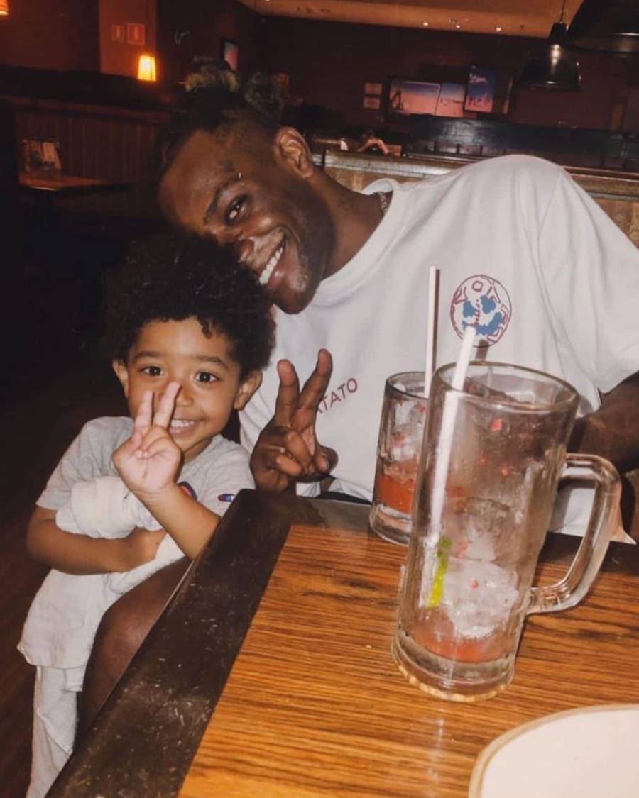 Foto de Pelé Milflows com seu filho em um restaurante. Ambos estão vestindo roupas brancas