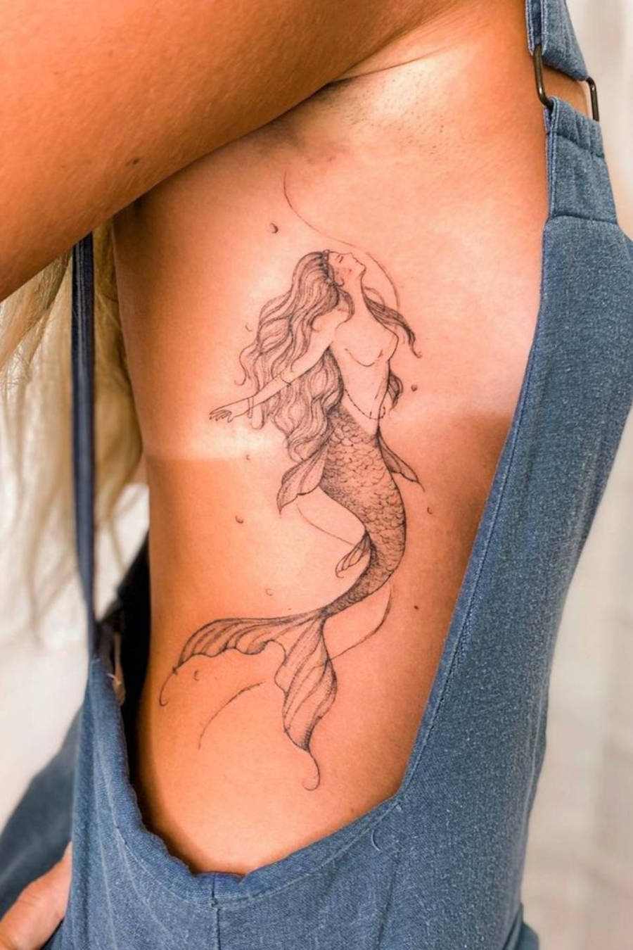 Foto de mulher tatuada com tattoo de sereiia na costela 