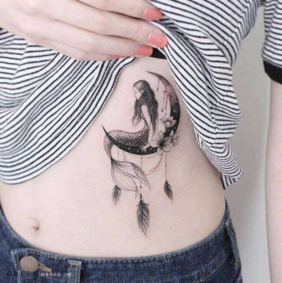 Foto de mulher com tatuagem de seria em cima de uma lua na costela