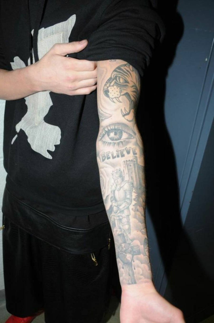 Foto do braço de Justin Bieber com diversas tatuagens e com destaque a tattoo "believe"