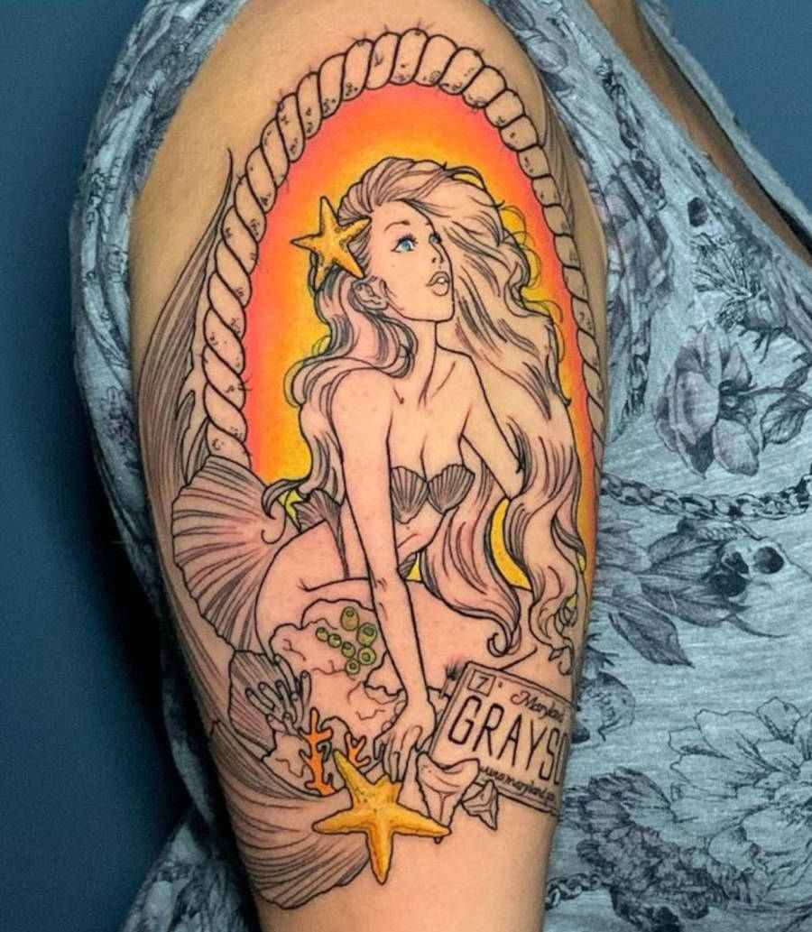 Foto de tatuagem de sereia colorida em tons de laranja no ombro de uma mulher