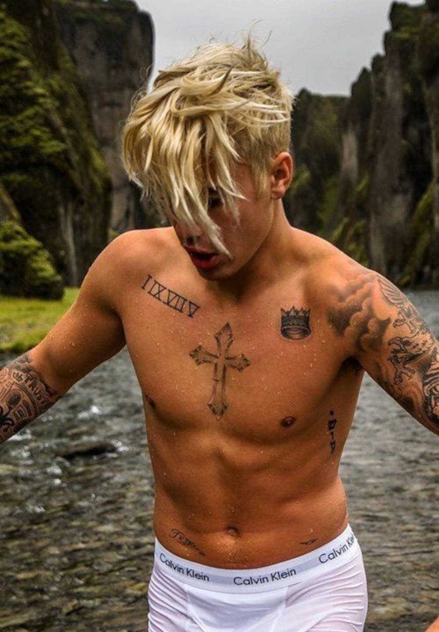 Foto de Justin Bieber com o cabelo loiro e destaque para a tattoo de coroa 