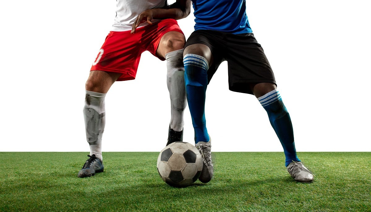 Foto mostra dois jogadores de times opostos lutando pela posse de bola