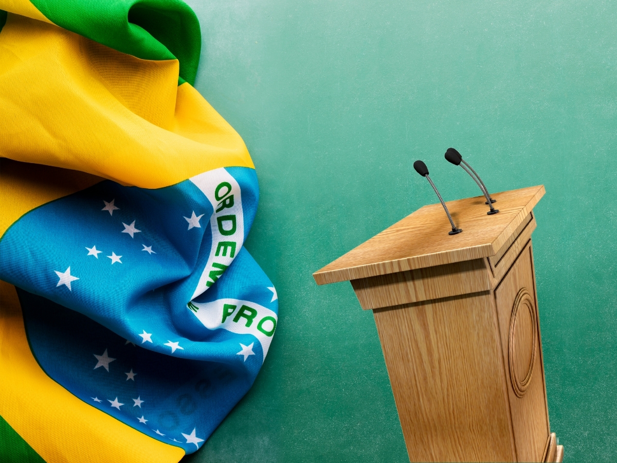 Foto de bandeira do brasil e púlpito com microfone.