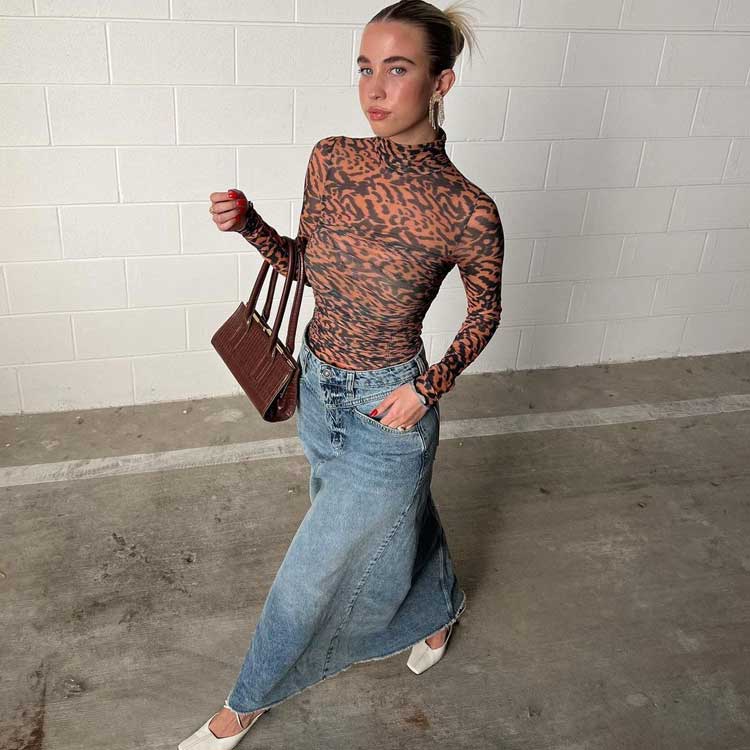 mulher usando saia jeans longa e camiseta de tule animal print