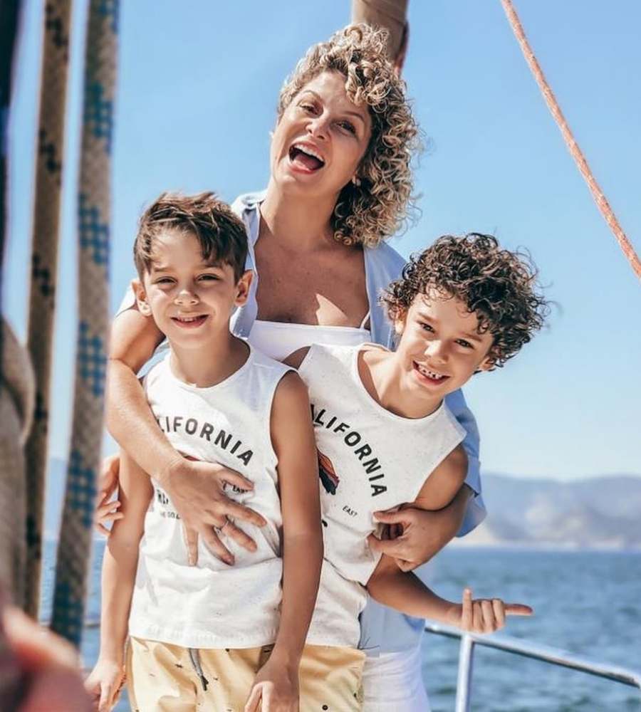 Foto da peoa com seus filhos. Os 3 estão abraços em embarcação no mar.