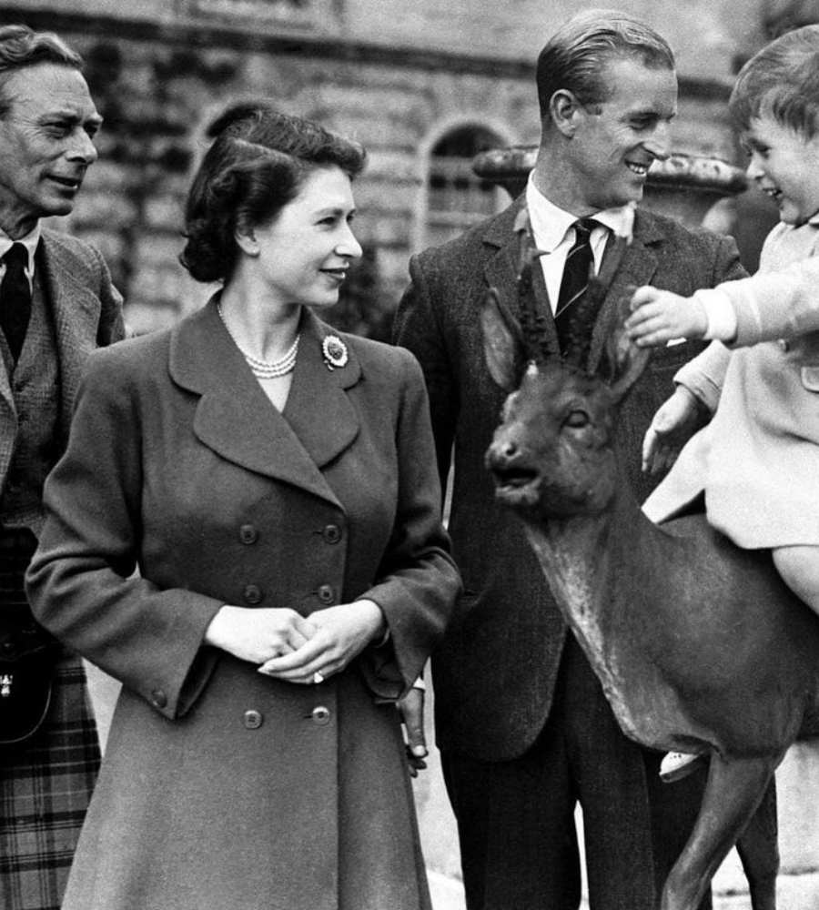 A monarca, o Príncipe Phillip, Charles III bebê em cima de animal e o Rei Jorge VI.