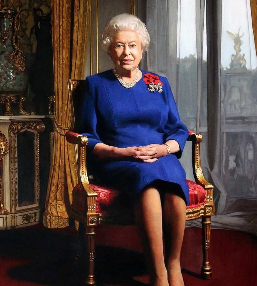 Foto da monarca sentada em cadeira luxuosa. Ela está usando vestido azul, colar de pérolas e broche.