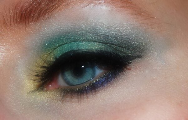 Foto de um olho azul com uma combinação de sombras verdes, amarelas e azuis