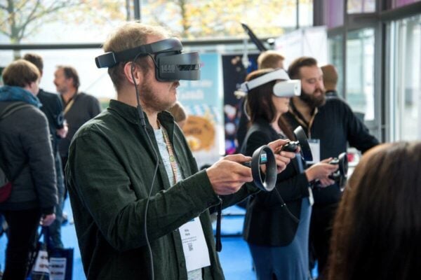 homem loiro em um evento de realidade virtual com, usando óculos e controle na mão