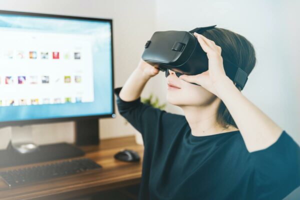 jovem usando óculos de realidade virtual na frente de um computador