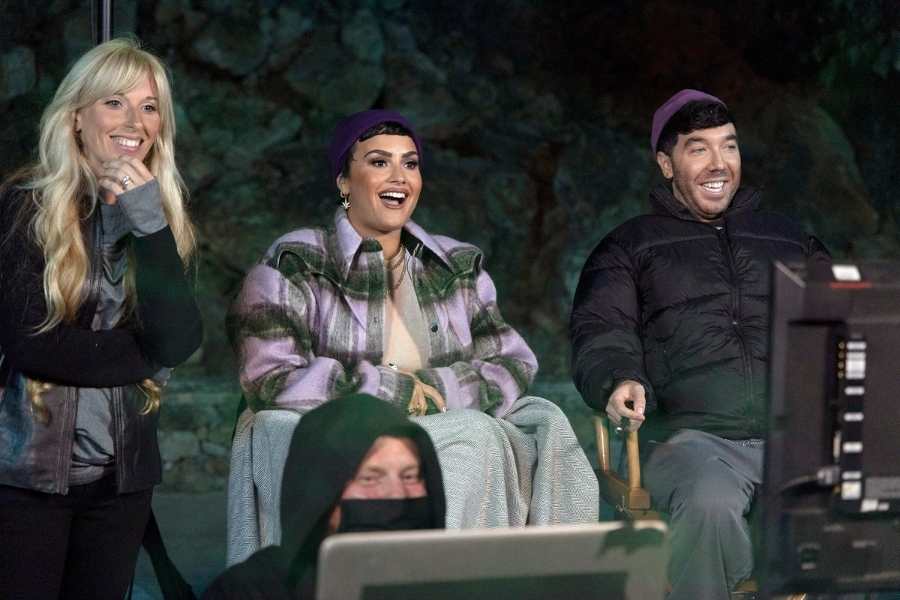 Foto de Demi Lovato e outras pessoas da série em caverna com computadores.