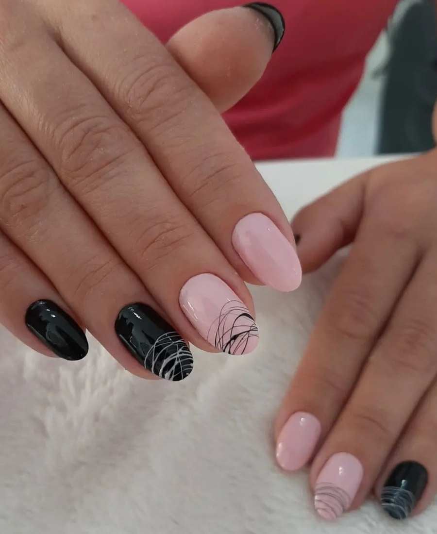 Mãos de mulher com dedo mínimo, anelar e polegar pintado de preto e dedo indicador e médio de nude. Dedo médio e anelar estão decorados com esmalte teia de aranha de cor inversa da unha pintada.