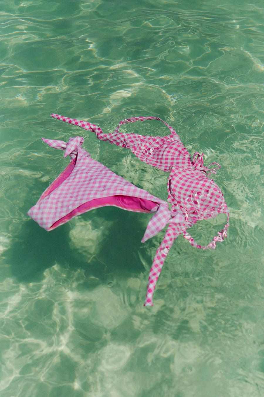 Foto de biquíni rosa com estampa vichy dentro de piscina