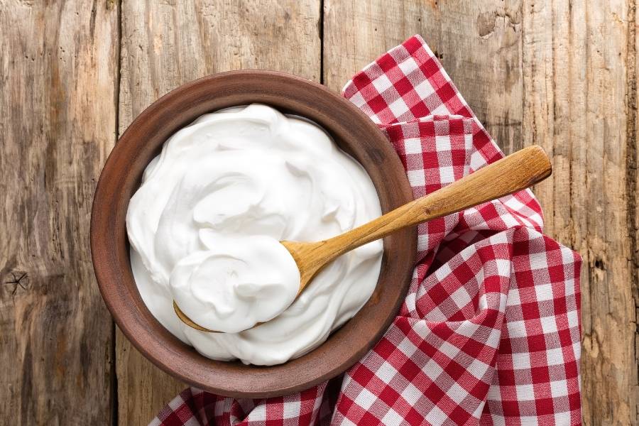 tigela de iogurte grego natural em cima de toalha xadrez vermelha