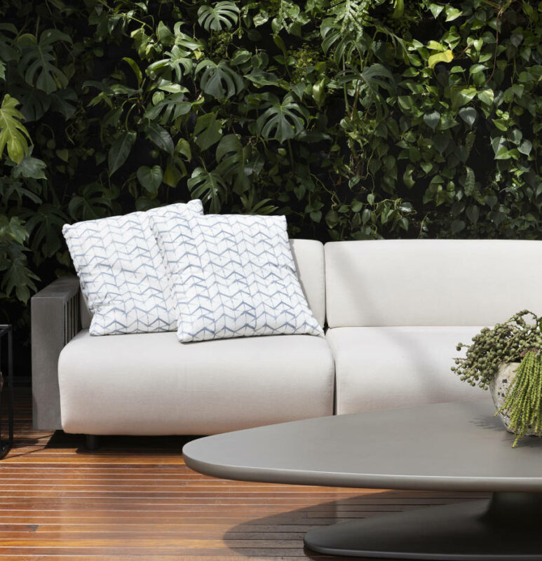 Jardim vertical e sofá branco com almofadas na Mostra Artefacto Beach & Country.
