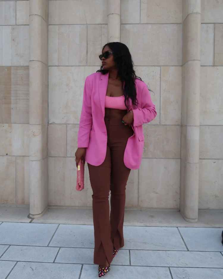 mulher com calça marrom, top e blazer rosa