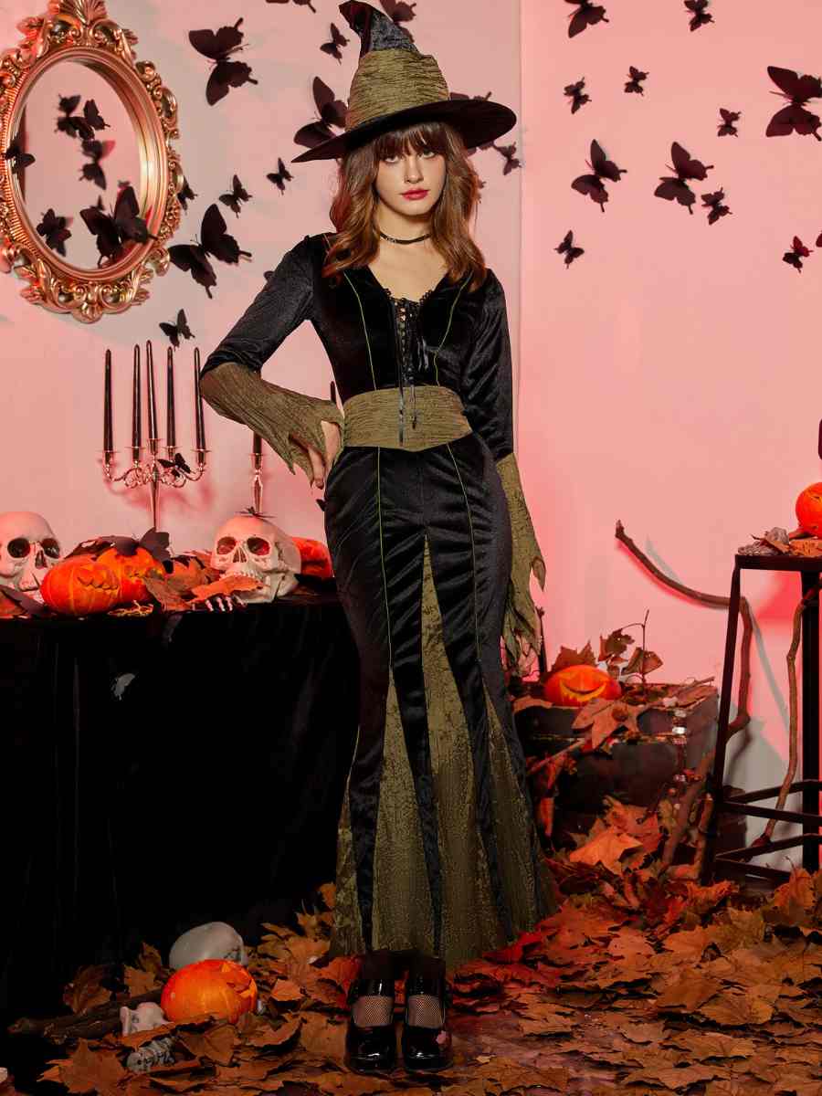 Foto de mulher com fantasia de bruxa para o Halloween. Vestido preto e verde comprido com chapéu.