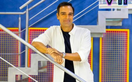 Foto de Tadeu Schmidt sorrindo na escada do BBB para ilustrar a matéria de quanto os participantes do BBB ganham por semana