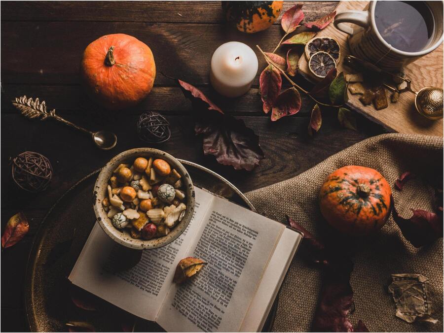 ritual de dia das bruxas com um livro aberto, abóbora e outros elementos em uma mesa de madeira