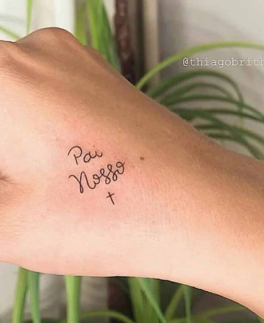 Tatuagem de Pai Nosso no braço de uma pessoa.