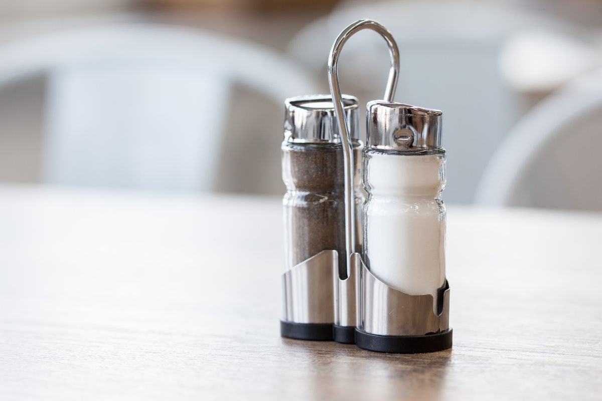 foto de galheteiro de metal com sal e pimenta em cima de mesa de restaurante