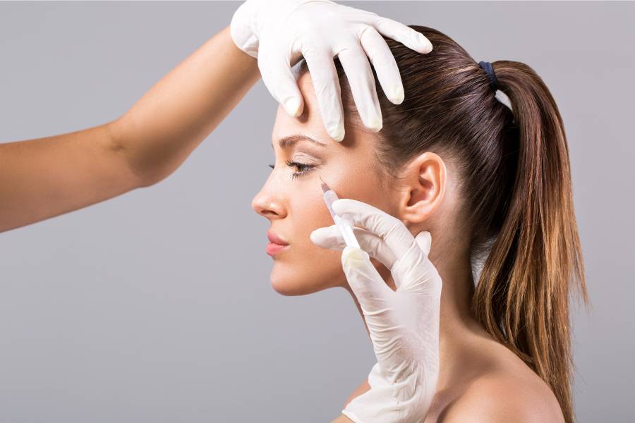 foto de esteticista com luvas aplicando seringa com Botox no rosto de uma mulher
