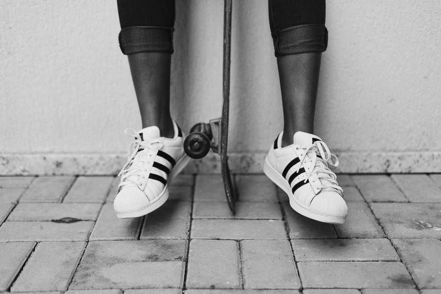 foto em preto e branco de mulher usando tênis da Adidas de couro e segurando skate