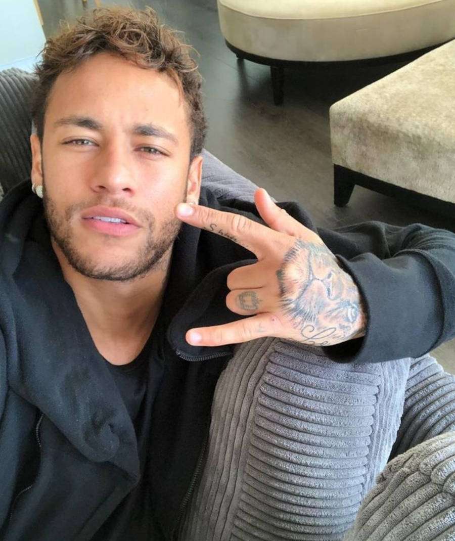Foto de Neymar fazendo símbolo do Rock n' Roll mostrando suas tatuagens na mão, inclusive, a tattoo de coroa de rainha