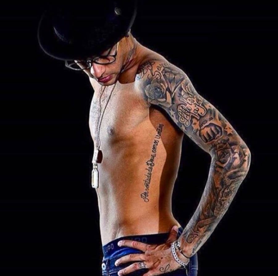 Foto de Neymar mais novo de lado, olhando para sua tatuagem na costela