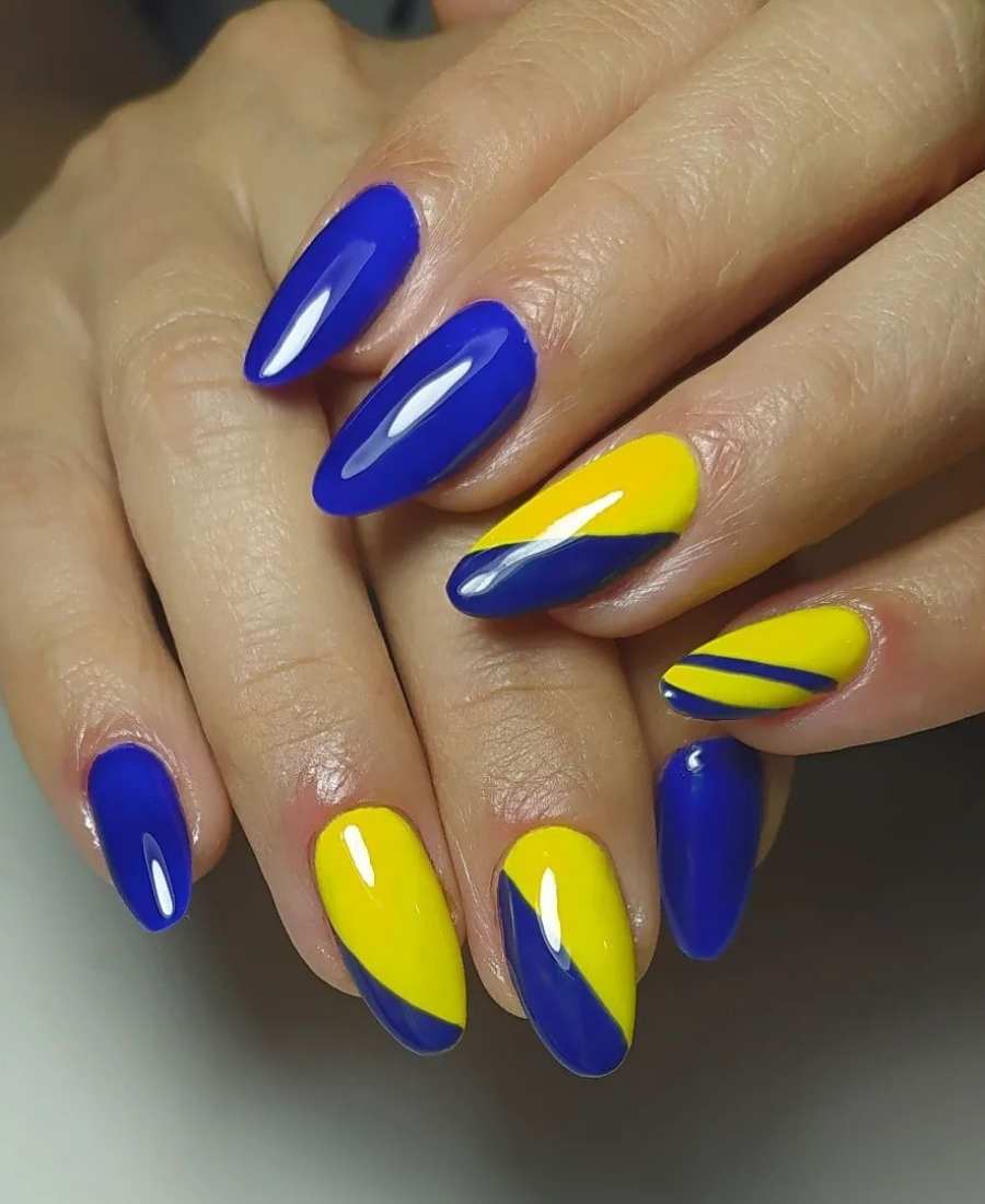 Imagem de mão com unhas decoradas para a Copa do Mundo 2022. Cores usadas: azul e amarelo. Polegar, indicador e médio, azul. Anelar e mínimo, azul e amarelo. 