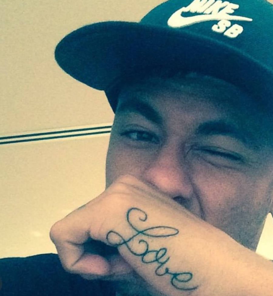 Foto de Neymar mais novo com a mão na boca e sua tatuagem "love" à mostra