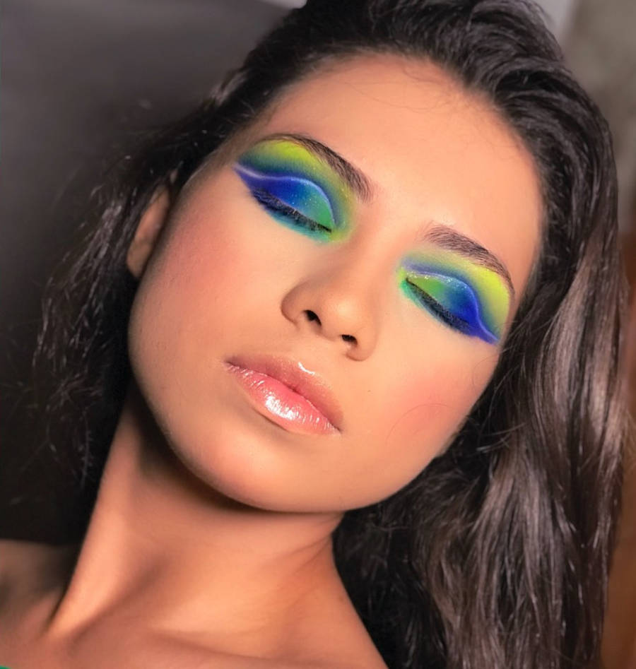 Foto de mulher com os olhos fechados com maquiagem para copa com as cores da bandeira do Brasil