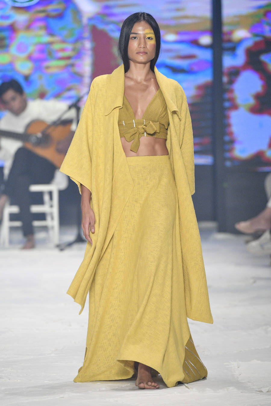 Modelo com traços de índia com roupa amarela.