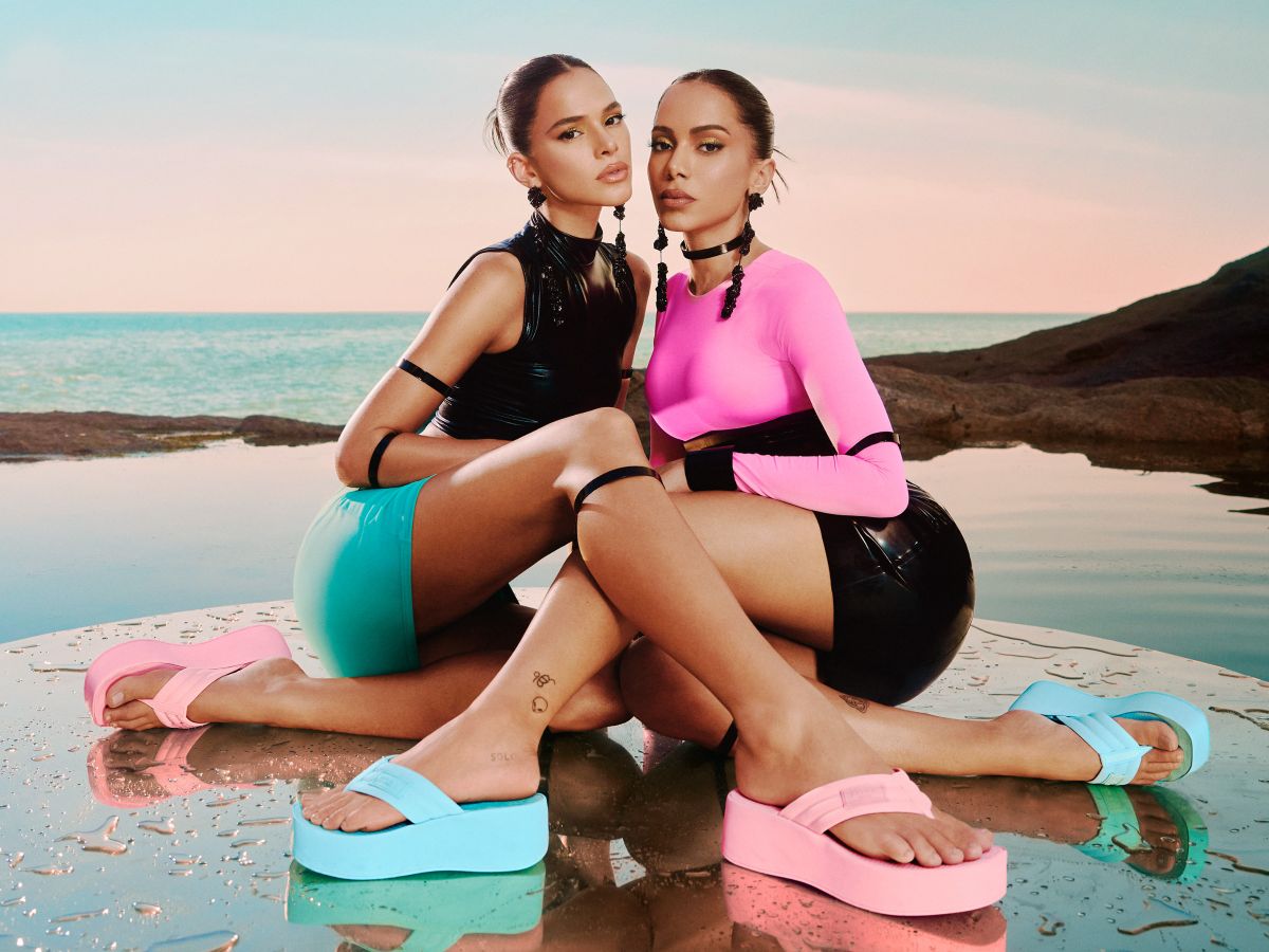 Foto de Anitta e Bruna Marquezine para campanha da marca de sandálias Brizza. As duas estão sentadas bem próximas e sobre água.