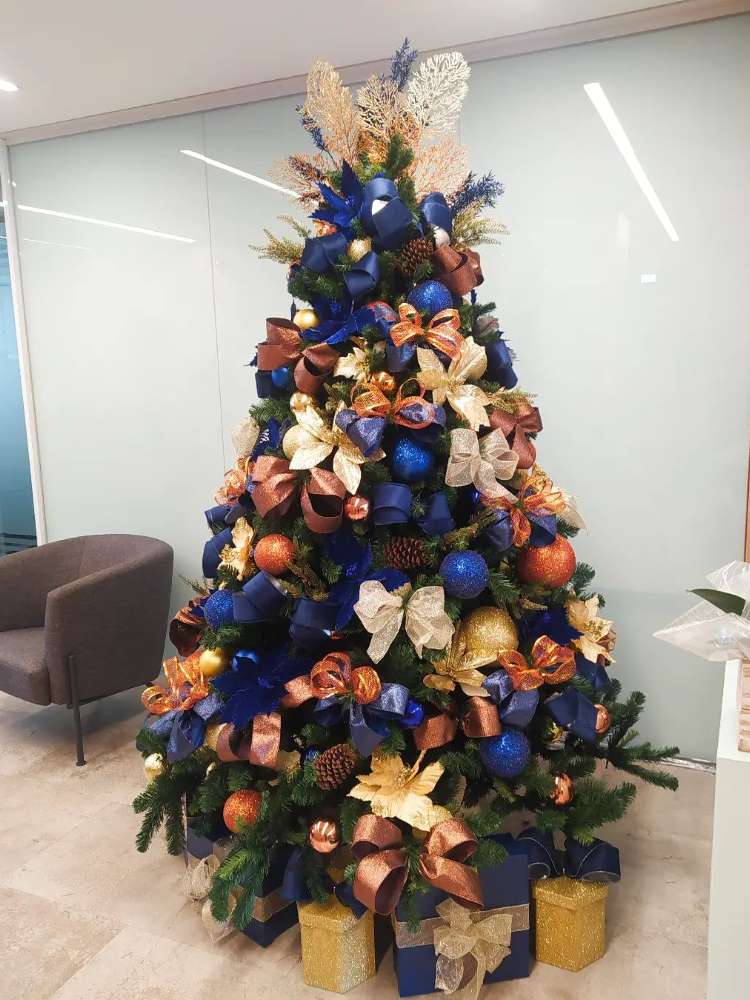 Árvore de Natal com enfeites laranjas, azuis e rosas. 