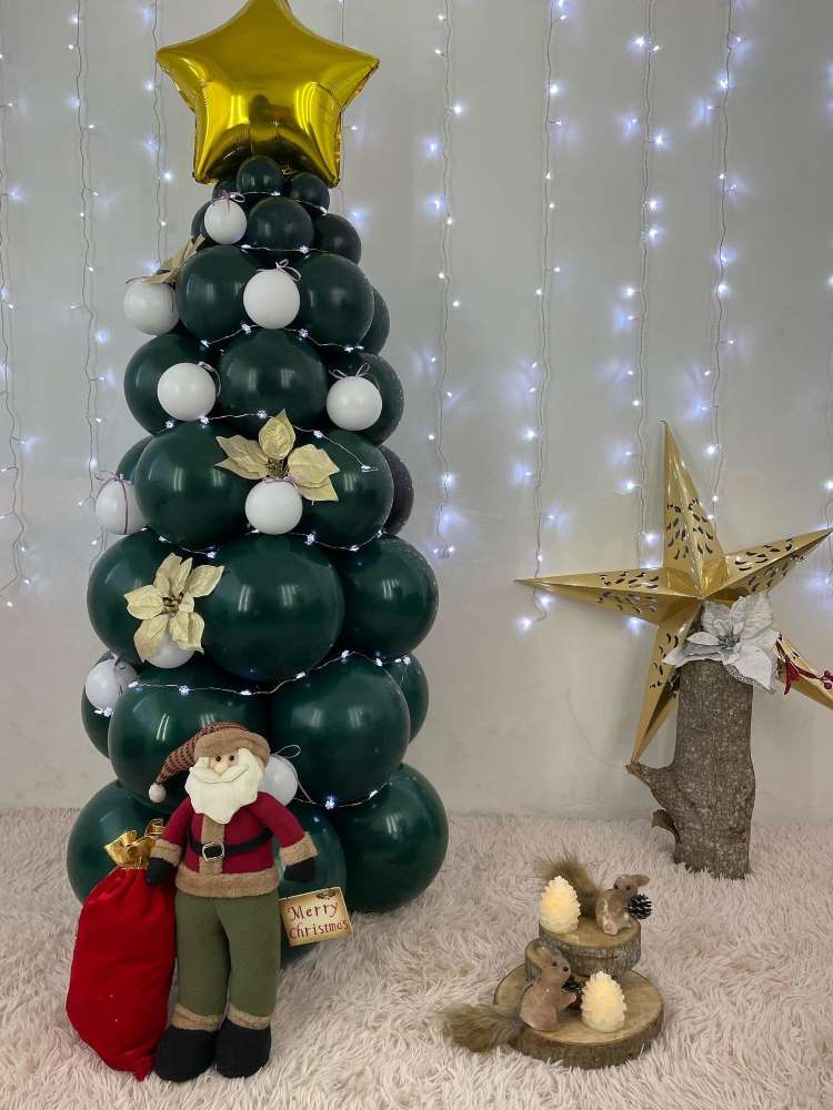 Árvore de Natal feita com bixigas verdes, enfeites em branco e dourado, além de um Papai Noel.