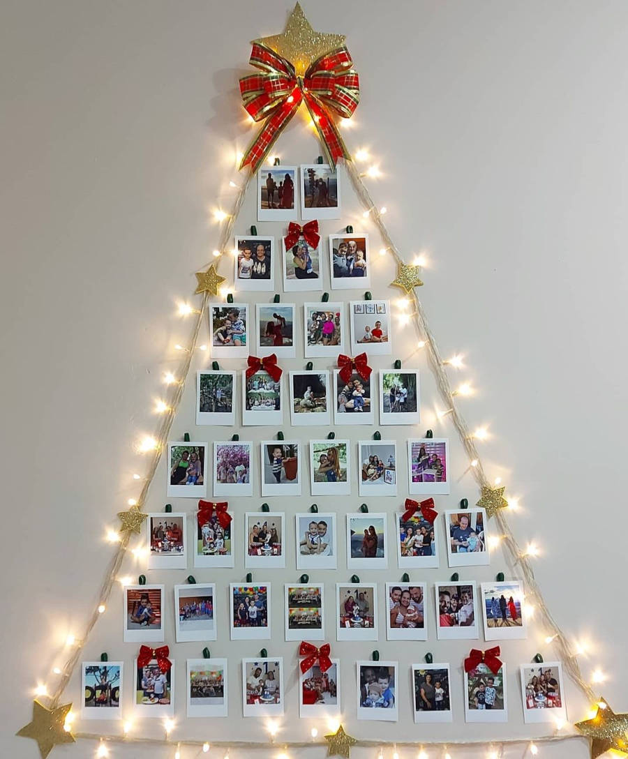 Árvore de Natal com fotos de polaroid e enfeitadas com laços e luzes.