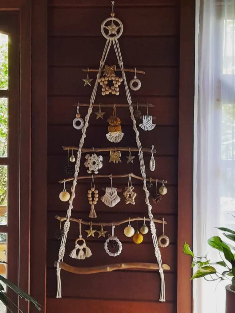 Árvore de Natal em macramê  e com galhos pendurada na porta 