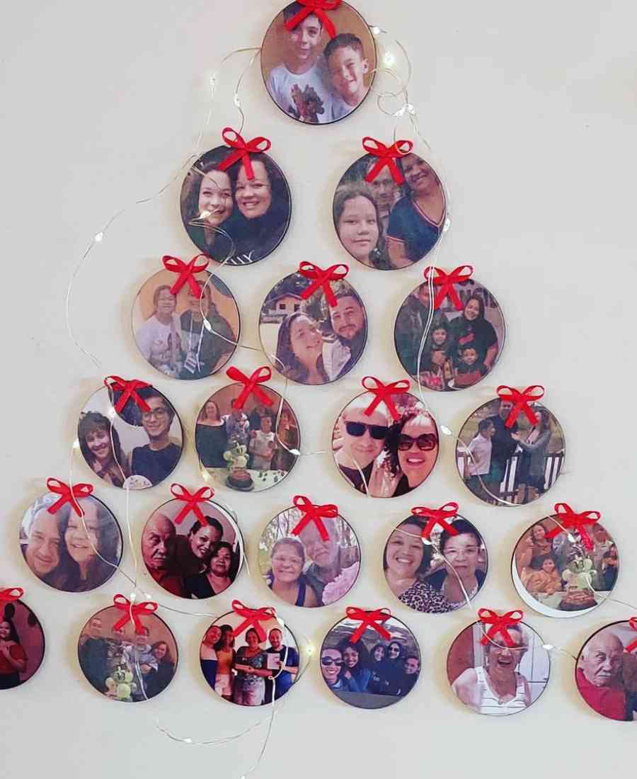 Foto de árvore de natal feita com fotos da família na parede. 