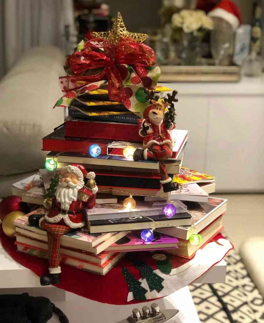 Foto de árvore de Natal feita de livros com decorações natalinas.