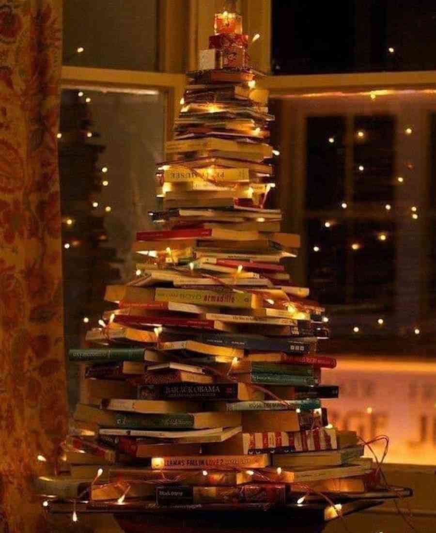 Foto de árvore de Natal feita de livros com decorações natalinas.